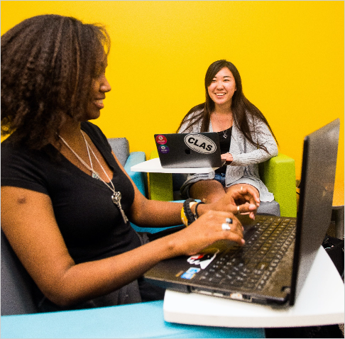 students smiling and looking at laptops