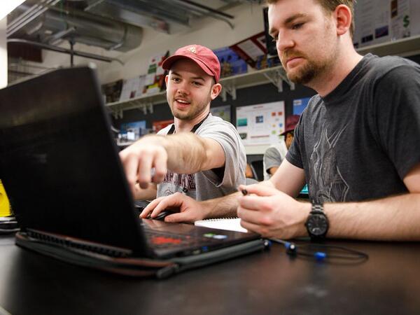 Michael Dumse (left) pointing at laptop screen in front of Philip Faint (right)