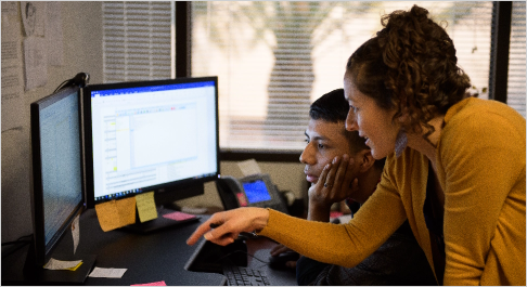 Two employees working at a computer in an office